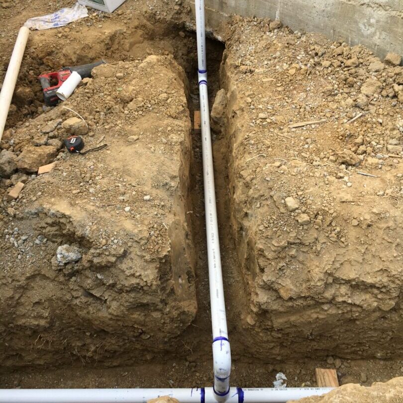 A trench with pipes and dirt on the ground.